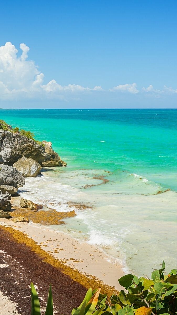 Plage de Tulum avec ruines mayas sur la falaise et végétation tropicale face à la mer turquoise