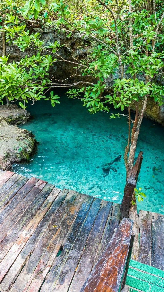 Cénote souterrain avec eau turquoise et passerelle en bois dans la jungle du Yucatán