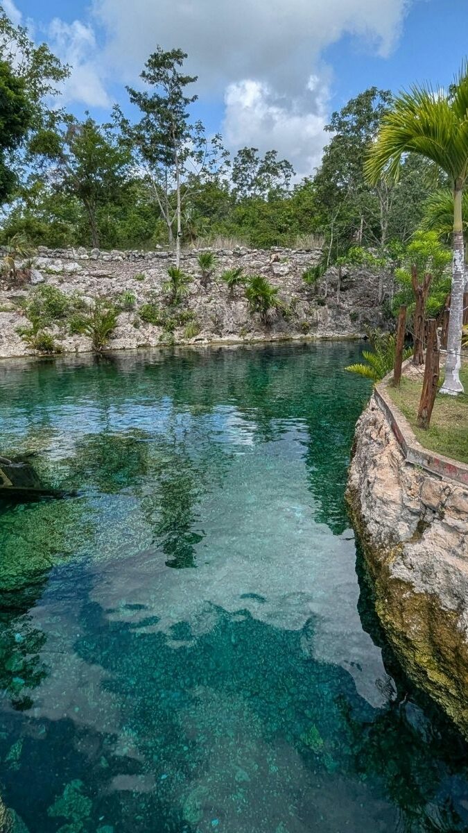 Cénote aménagé avec eau cristalline, pont en bois et palapa dans un cadre tropical