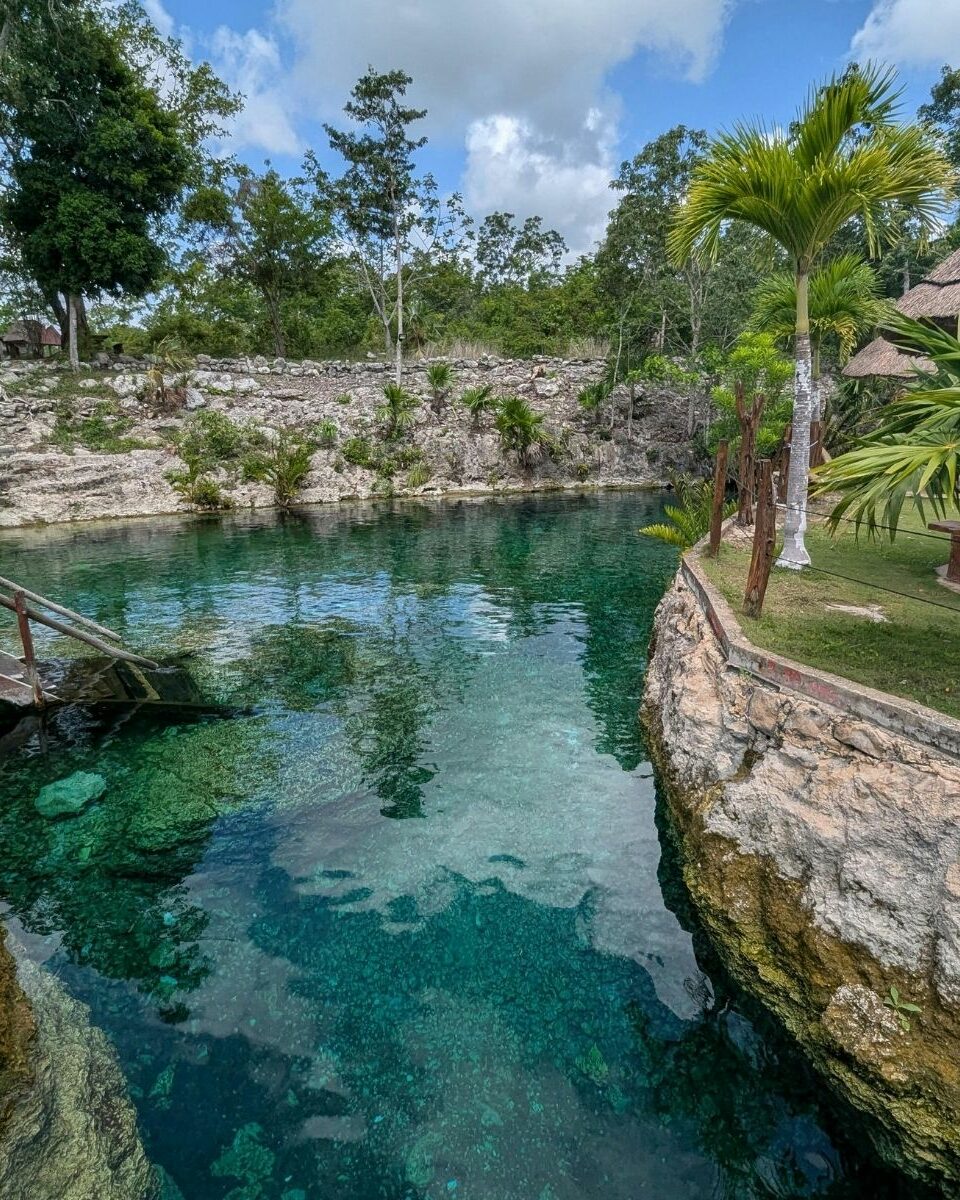 Cénote aménagé avec eau cristalline, pont en bois et palapa dans un cadre tropical