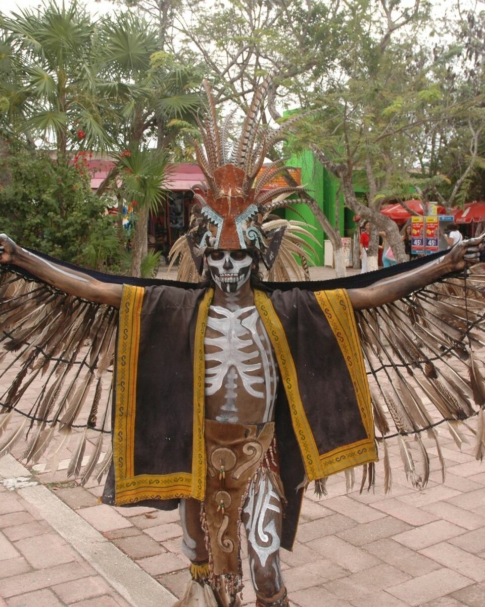 Danseur en costume traditionnel maya avec coiffe de plumes déployée lors d'une cérémonie