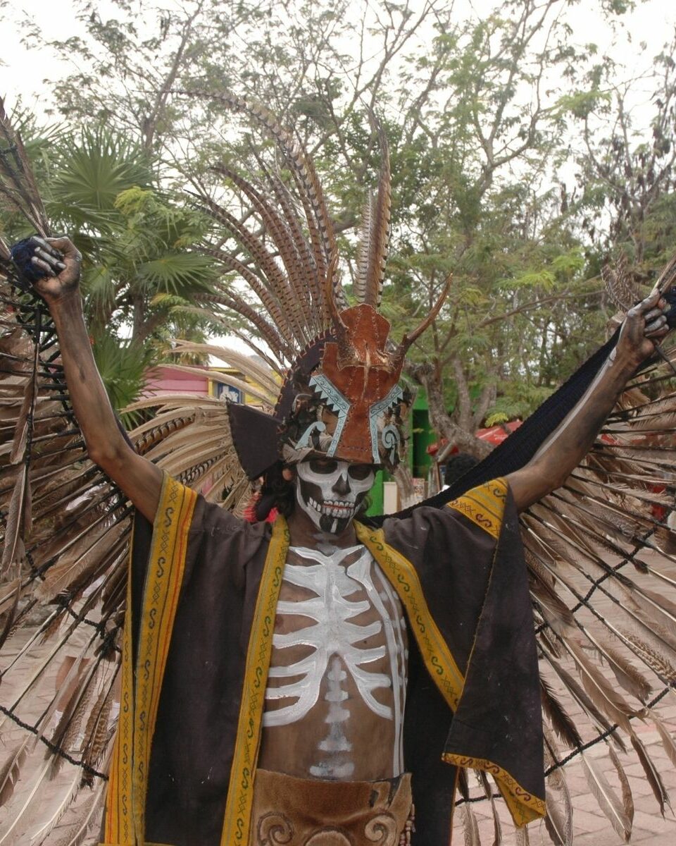 Danseur maya en tenue cérémonielle avec grande coiffe de plumes et peinture corporelle