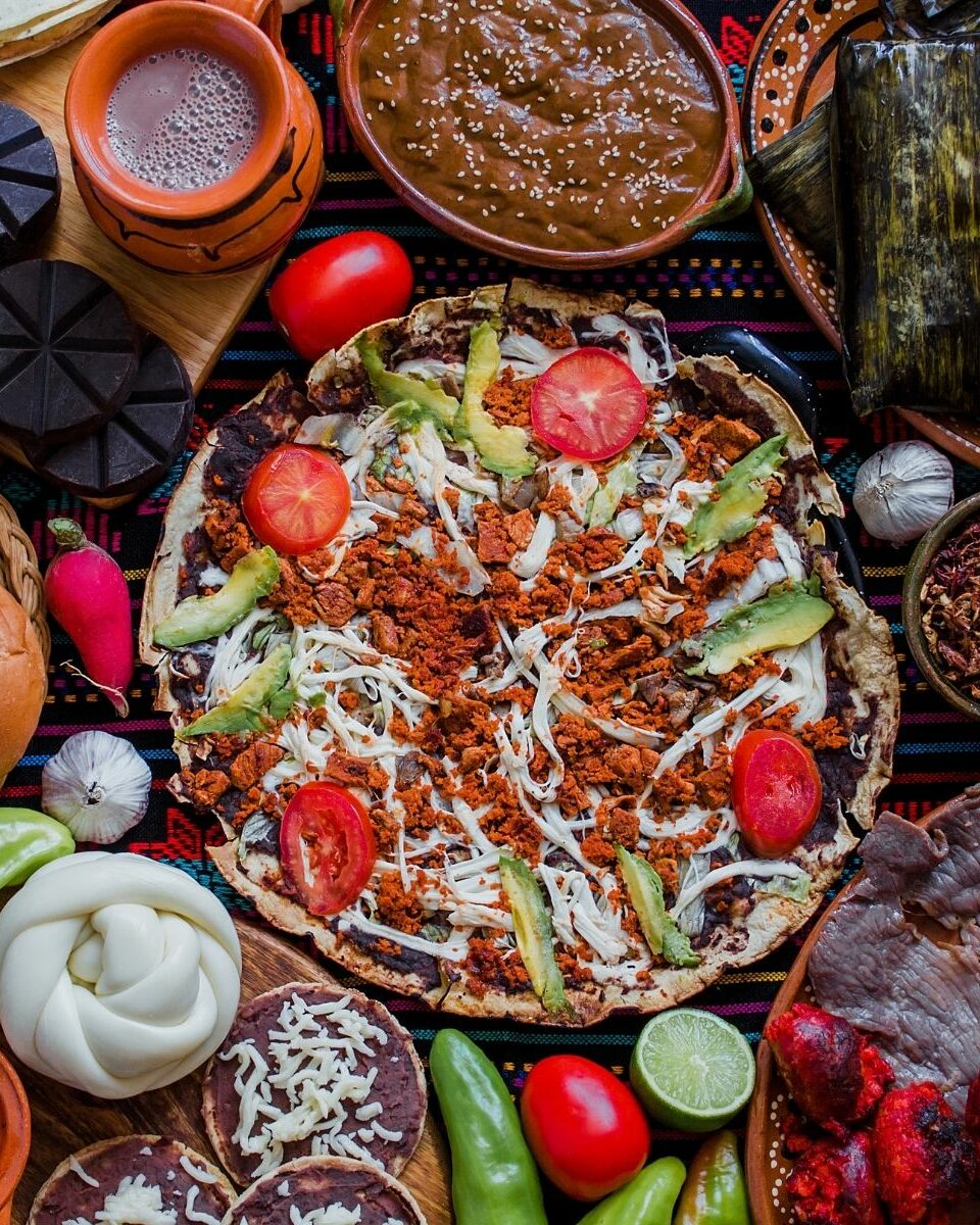 Table garnie de plats traditionnels mexicains avec tlayuda, tortillas, sauces et légumes frais