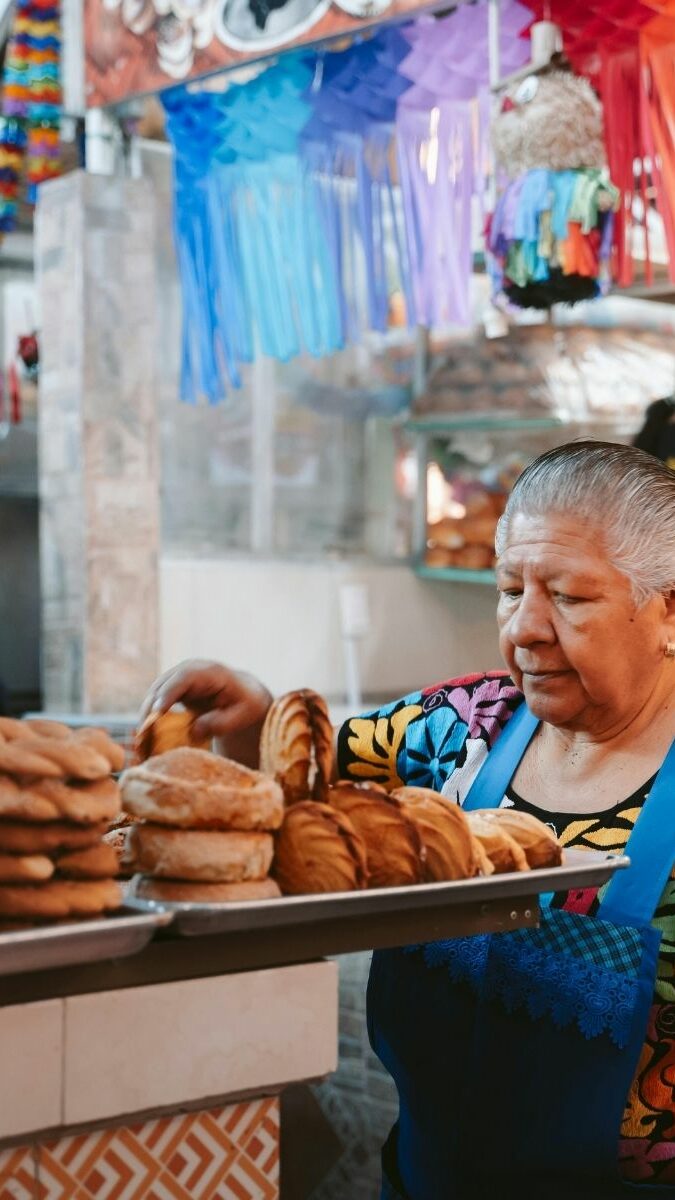 Vendeuse de pain traditionnel dans un marché mexicain avec décorations colorées