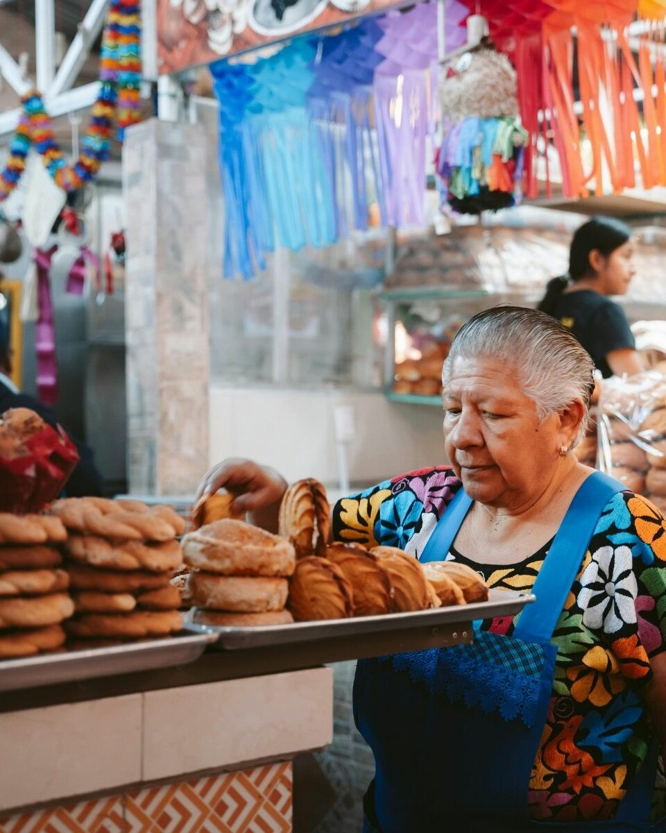Vendeuse de pain traditionnel dans un marché mexicain avec décorations colorées