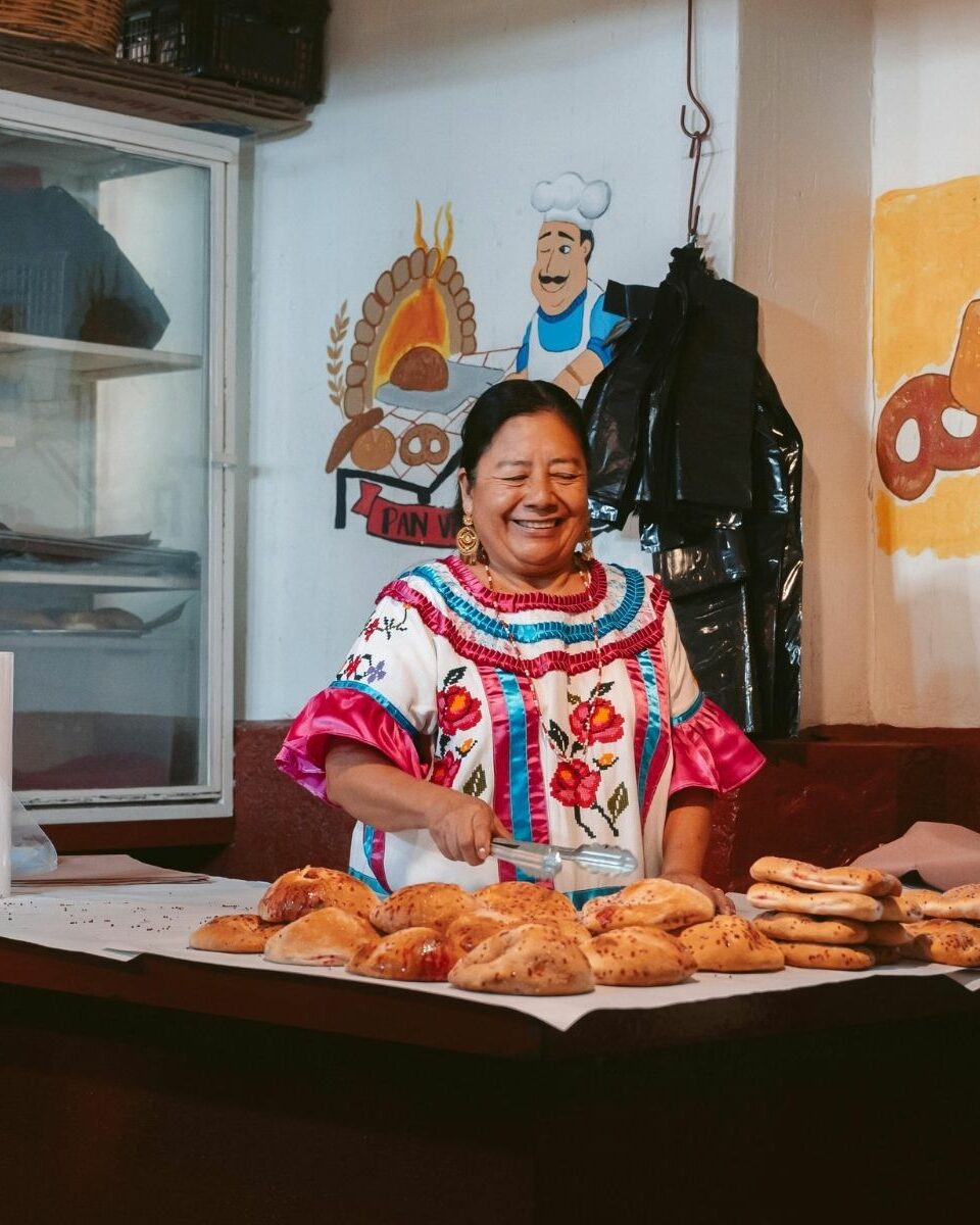 Boulangère mexicaine en blouse brodée traditionnelle présentant des pains artisanaux