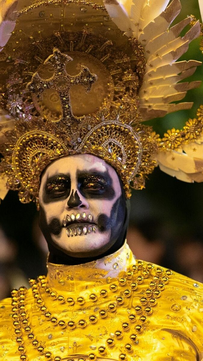 Homme maquillé en Catrina dorée avec coiffe lors des célébrations du Día de Muertos au Mexique