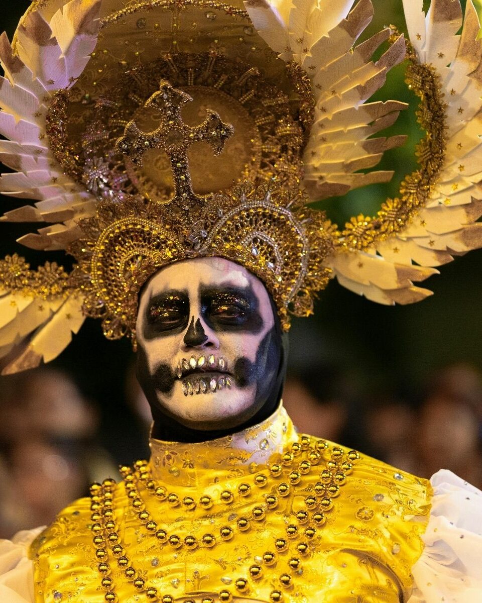Homme maquillé en Catrina dorée avec coiffe lors des célébrations du Día de Muertos au Mexique