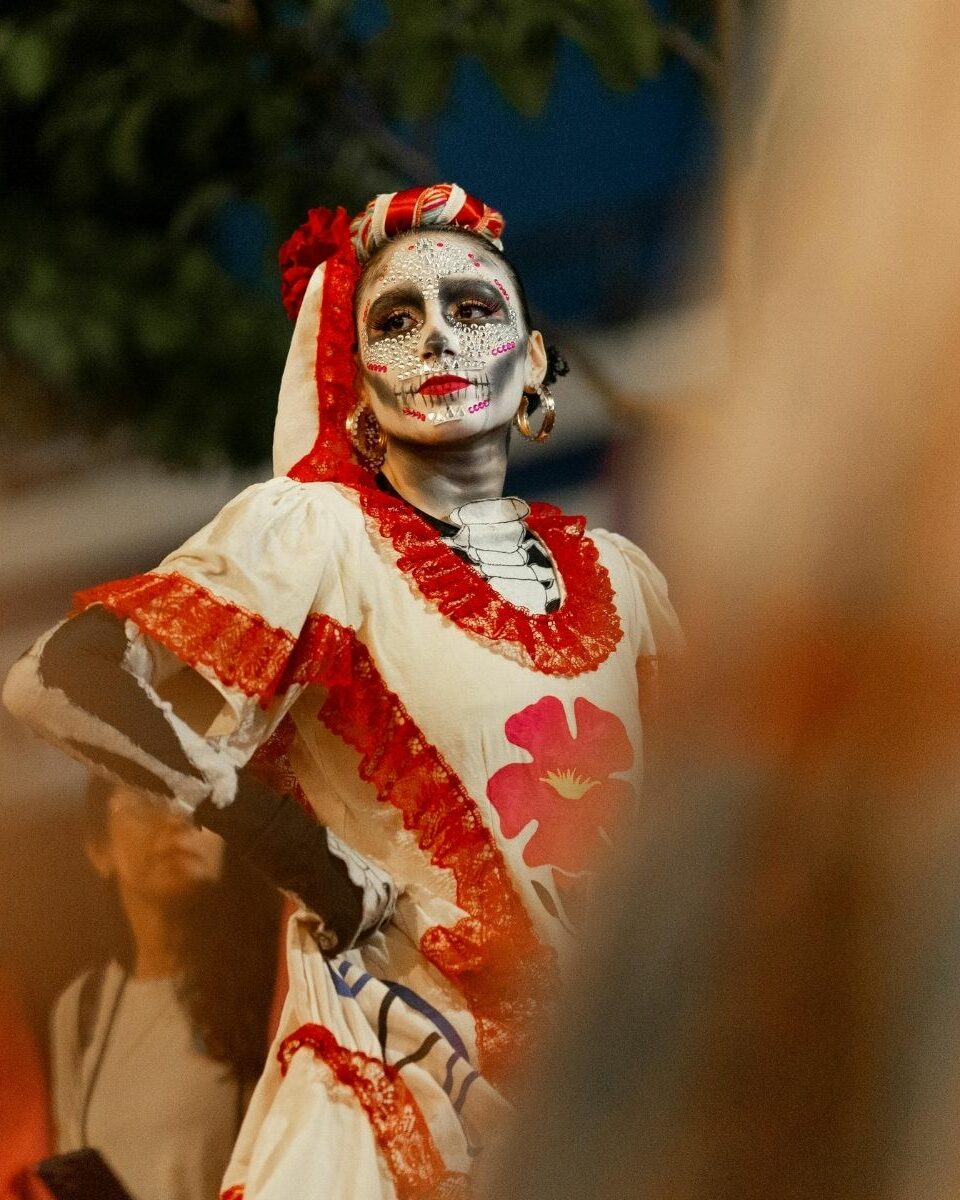 Femme maquillée en Catrina en robe blanche et rouge lors du Día de Muertos