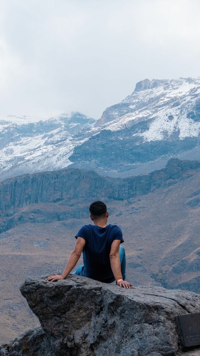 Randonneur contemplant le volcan enneigé Iztaccíhuatl assis sur un rocher