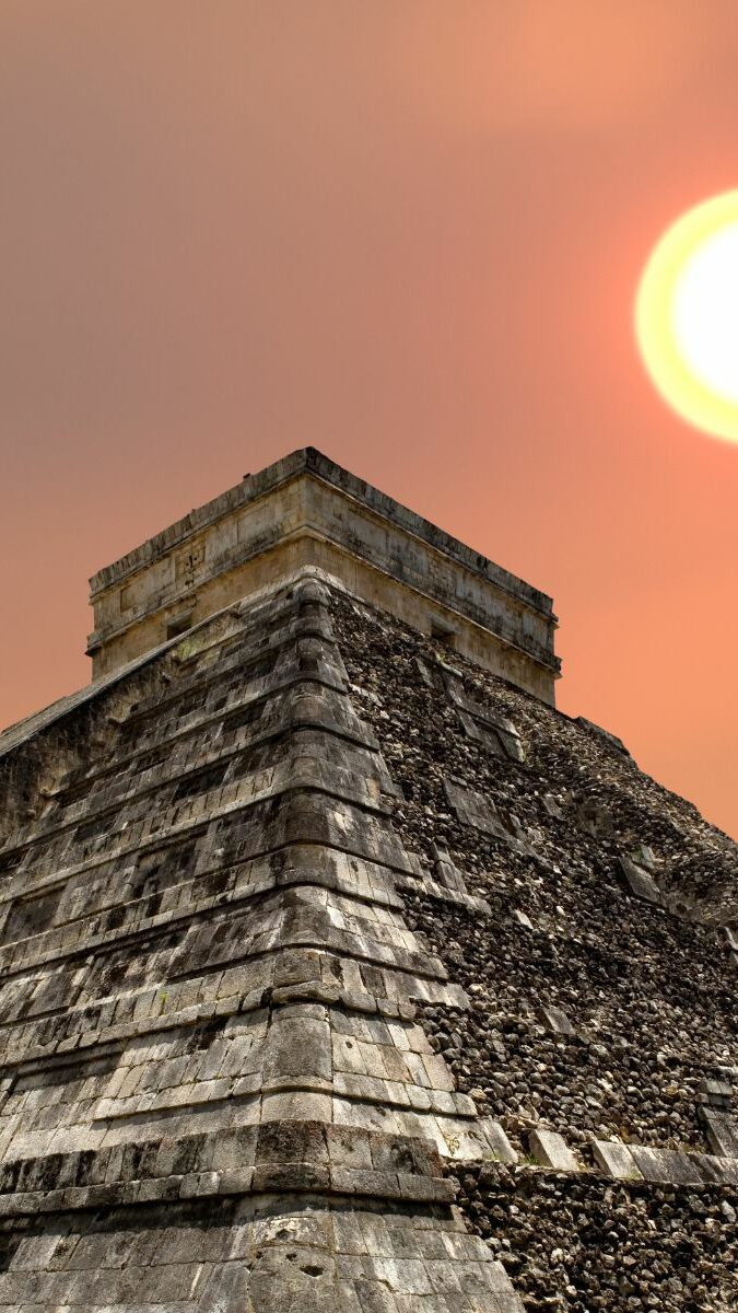 Pyramide de Kukulcán à Chichén Itzá au coucher du soleil avec ciel orangé