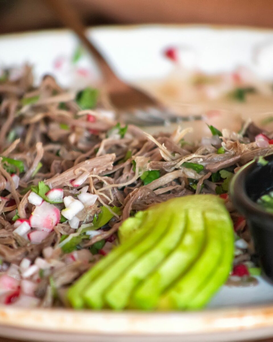Plat de barbacoa de bœuf effiloché servi avec radis, avocat et salsa verde