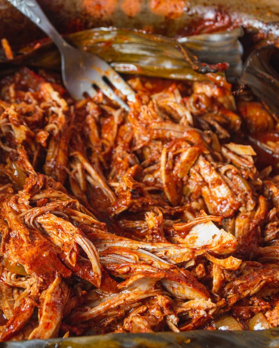 Cochinita pibil mijotée dans son jus rouge, viande de porc effilochée traditionnelle du Yucatán
