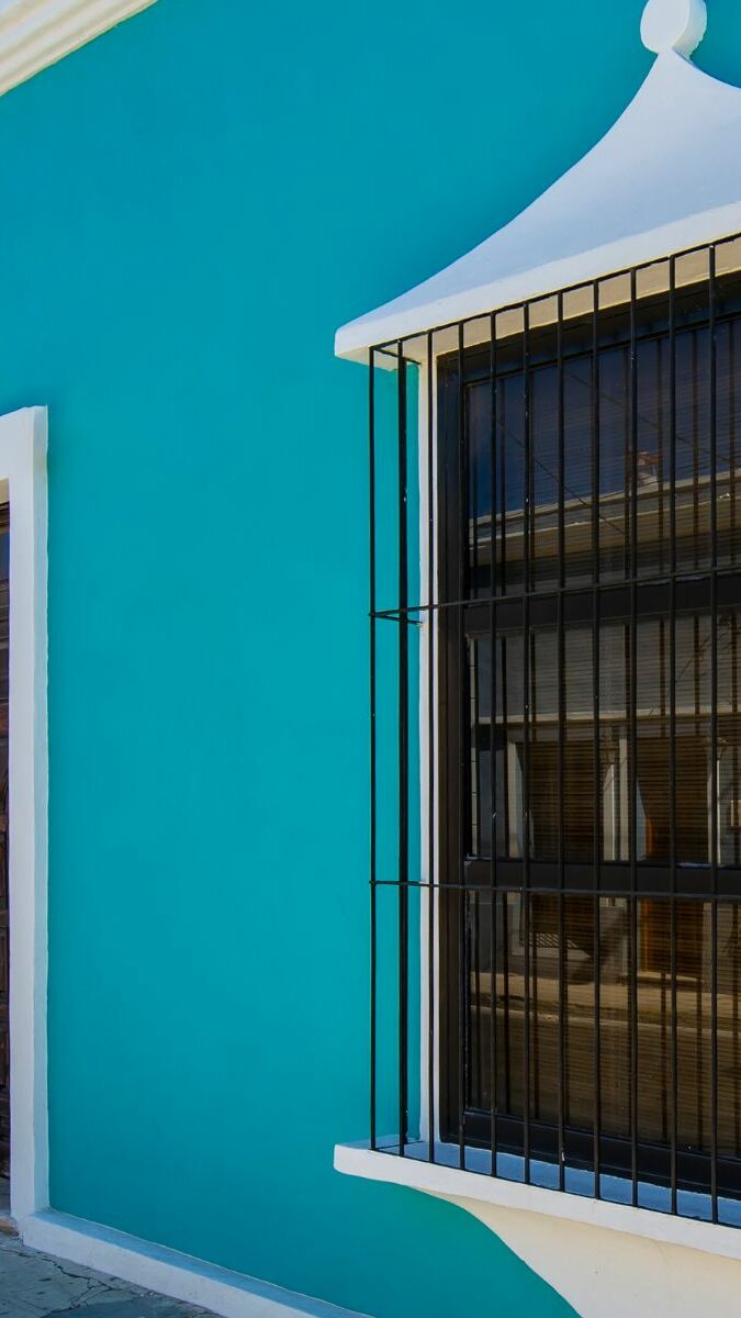 Façade coloniale turquoise et orange avec fenêtre à grille en fer forgé à Valladolid