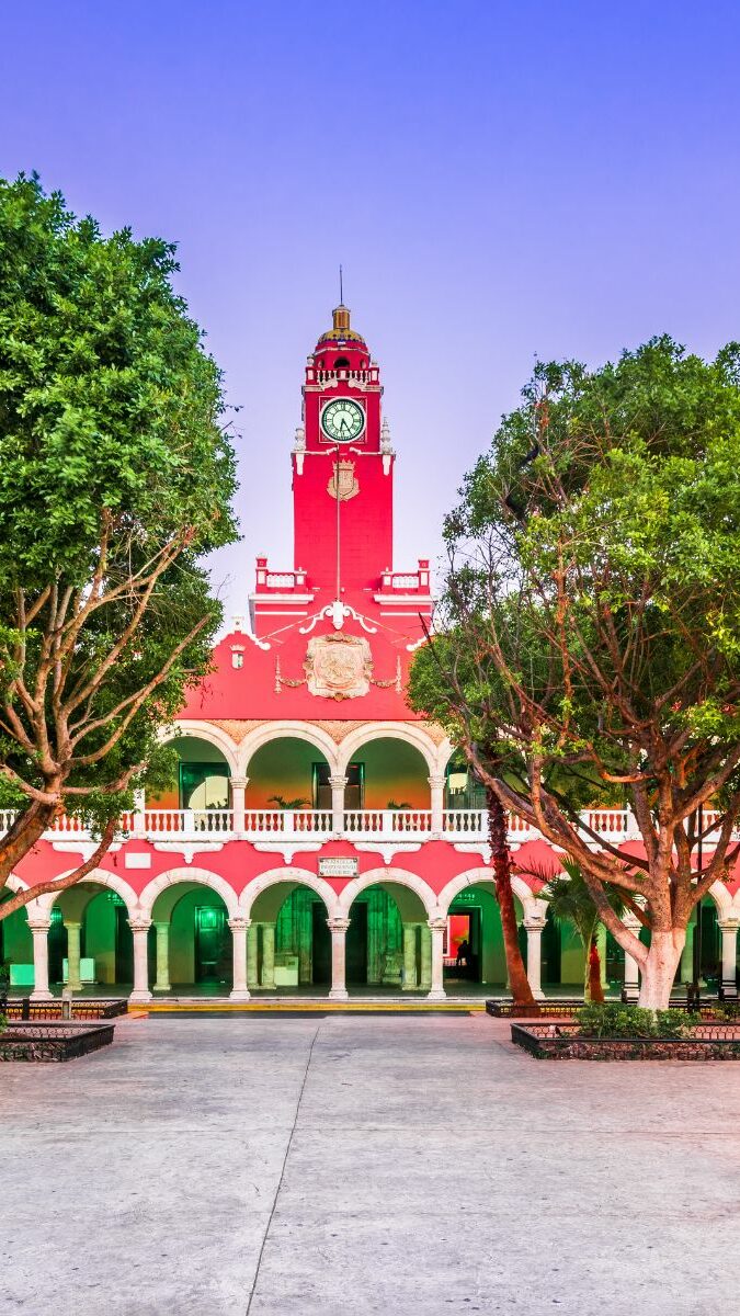 Place principale d'un village du Yucatán avec mairie rouge et blanche illuminée au crépuscule