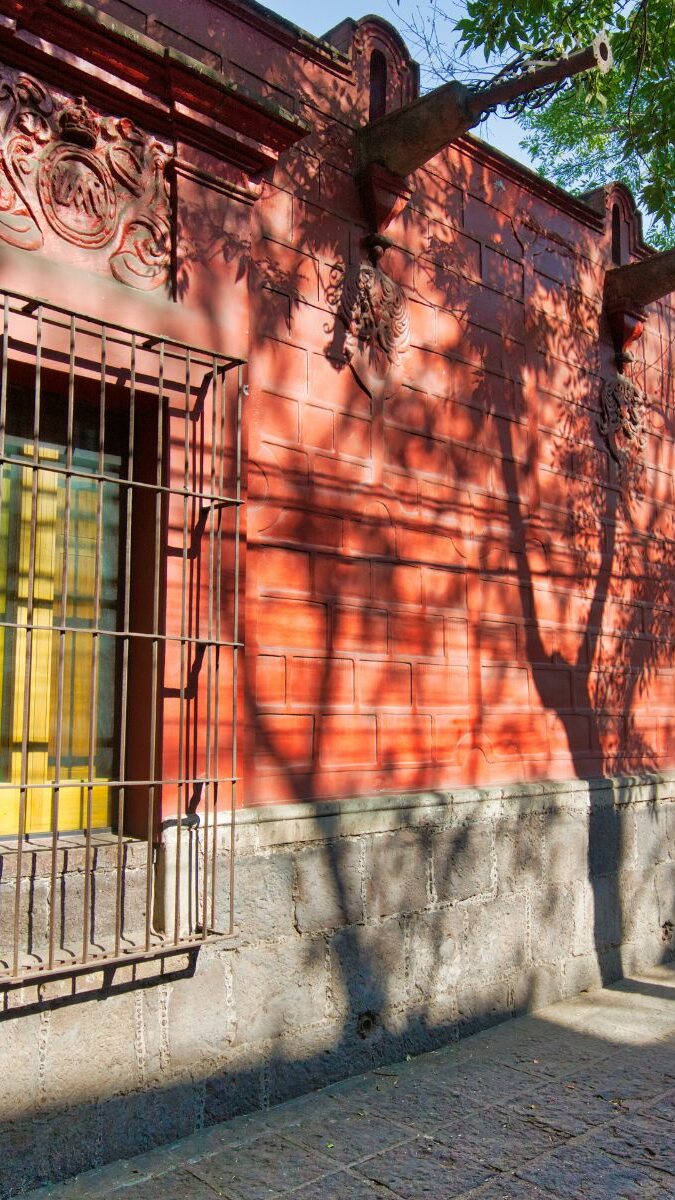 Façade rouge d'une maison coloniale avec fenêtres colorées dans le quartier de Coyoacán