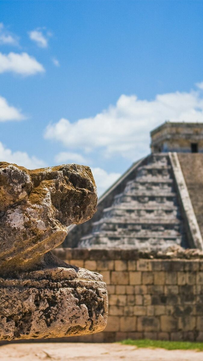 Tête de serpent à plumes et pyramide de Kukulcán à Chichén Itzá sous un ciel bleu